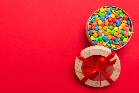 Set of different sweet candy in a paper box with a satin ribbon on a colored background. Holiday concept.の写真素材