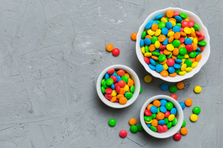 different colored round candy in bowl and jars. Top view of large variety of sweets and candies with copy space.の写真素材