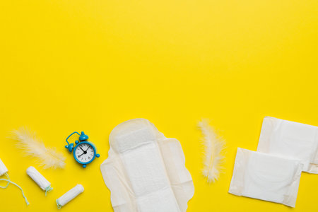 Ringing alarm clock with sanitary female tampons and menstrual sanitary pads. Medical concept of woman critical days and menstruation. Female daily hygiene. Copy space.の写真素材