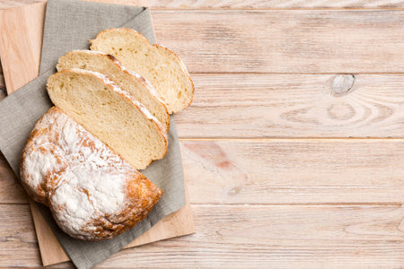 Freshly baked bread slices on cutting board against white wooden background. top view Sliced bread.の写真素材