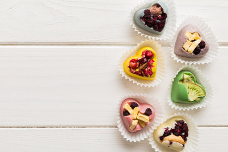 chocolate sweets in the form of a heart with fruits and nuts on a colored background. top view with space for text, holiday concept.の写真素材