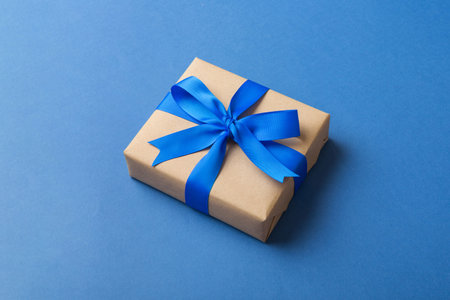 Wrapped christmas or other holiday handmade present in craft paper with colored ribbon. Present box, decoration of gift on table, top view with copy space.の写真素材