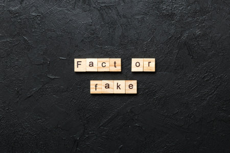 fact or fake word written on wood block. fact or fake text on table, concept.の写真素材