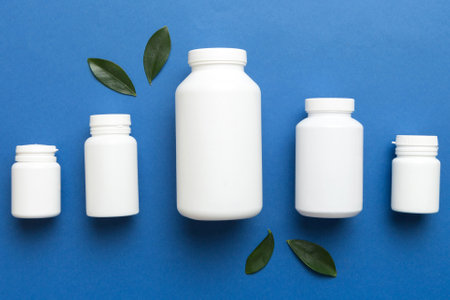 supplement pills with medicine bottle health care and medical top view. Vitamin tablets. Top view mockup bottle for pills and vitamins with green leaves, natural organic bio supplement, copy space.の写真素材