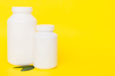 supplement pills with medicine bottle health care and medical top view. Vitamin tablets. Top view mockup bottle for pills and vitamins with green leaves, natural organic bio supplement, copy space.の写真素材