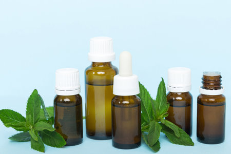 Natural Mint Essential Oil in a Glass Bottle. organic cosmetics with herbal extracts of mint on colored background.の写真素材