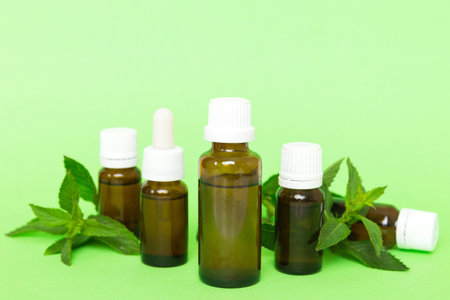 Natural Mint Essential Oil in a Glass Bottle. organic cosmetics with herbal extracts of mint on colored background.の写真素材