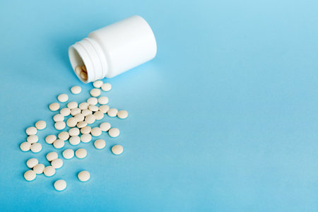 Medicine bottle and white pills spilled on a light background. Medicines and prescription pills flat lay background. White medical pills and tablets spilling out of a drug bottle.の写真素材