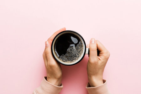 Minimalistic style woman hand holding a cup of coffee on Colored background. Flat lay, top view cappuccino cup. Empty place for text, copy space. Top view, flat lay.の写真素材