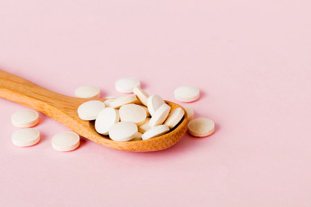 Heap of white pills on colored background. Tablets scattered on a table. Vitamins and dietary supplements concept.の写真素材