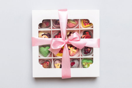 Box with sweet chocolate candies on color background, Various candy sweets. Valentines day gift box. Top view flat lay with copy space.の写真素材