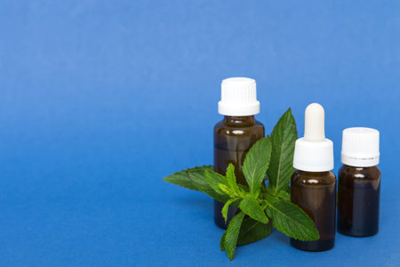 Natural Mint Essential Oil in a Glass Bottle. organic cosmetics with herbal extracts of mint on colored background.の写真素材