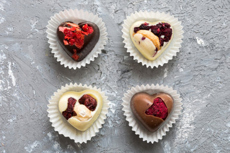 chocolate sweets in the form of a heart with fruits and nuts on a colored background. top view with space for text, holiday concept.の写真素材
