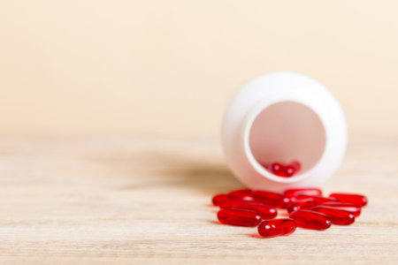 Red pills spilled around a pill bottle. Medicines and prescription pills flat lay background. Red medical capsules.の写真素材