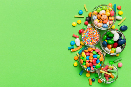 different colored round candy in bowl and jars. Top view of large variety of sweets and candies with copy space.の写真素材