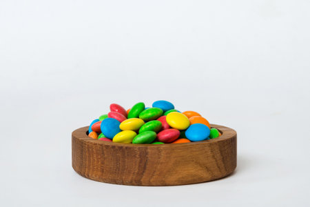 Multicolored candies in a bowl on a colored background. birthday and holiday concept. Top view with copy space.の写真素材