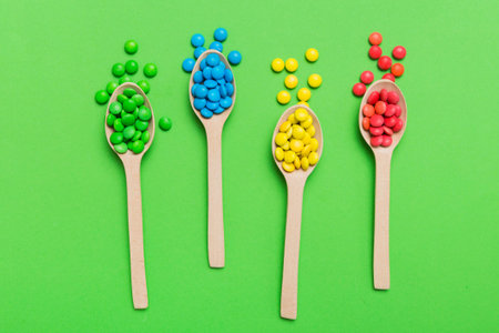 delicious colorful sweet candies on spoon on colored background. Confectionery decor top view with copy space.の写真素材
