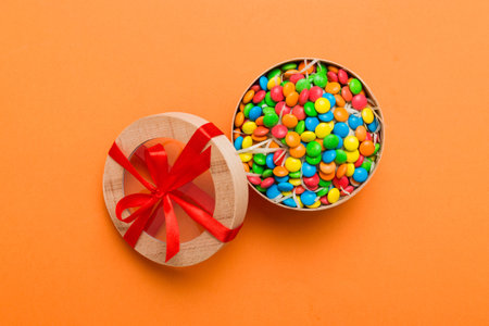 Set of different sweet candy in a paper box with a satin ribbon on a colored background. Holiday concept.の写真素材