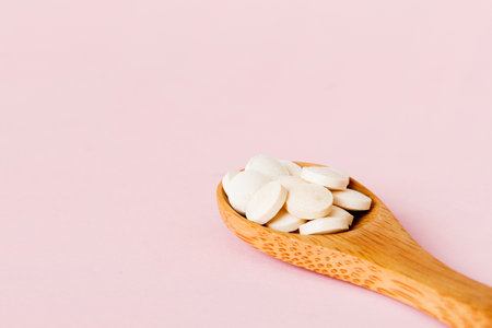 Heap of white pills on colored background. Tablets scattered on a table. Vitamins and dietary supplements concept.の写真素材