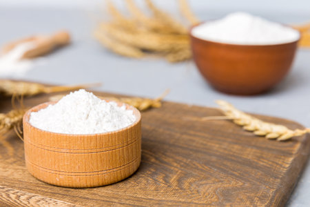 Flat lay of Wheat flour in wooden bowl with wheat spikelets on colored background. world wheat crisis.の写真素材