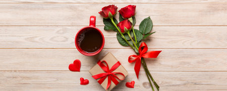 Valentine day composition with coffee cup, rose flower and gift box on table. Top view, flat lay. Holiday concept.の写真素材