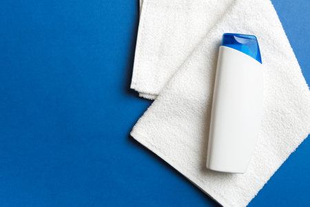 Cosmetic shampoo bottle mockup with towels on a colored table. Bathroom background, toilet...