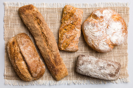 Assortment of freshly baked bread with napkin on rustic table top view. Healthy unleavened bread. French bread.の写真素材