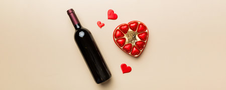 Bottle of red wine on colored background for Valentine Day with gift and chocolate. Heart shaped with gift box of chocolates top view with copy space.の写真素材