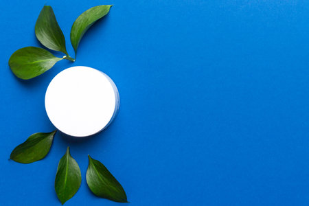 Organic cosmetic product with green leaves on color background. Copy space, flat lay.の写真素材