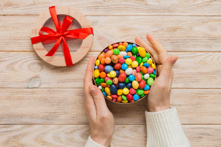 Female hands with delicious candies in box on color background.の写真素材