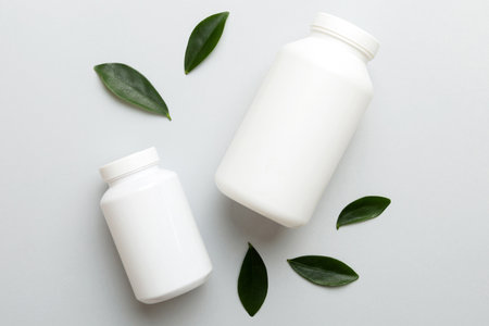 supplement pills with medicine bottle health care and medical top view. Vitamin tablets. Top view mockup bottle for pills and vitamins with green leaves, natural organic bio supplement, copy space.の写真素材