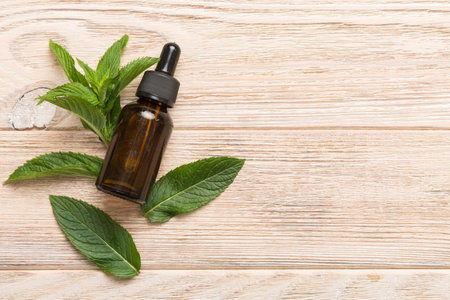 Natural Mint Essential Oil in a Glass Bottle. organic cosmetics with herbal extracts of mint on colored background.の写真素材