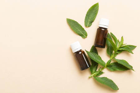 Natural Mint Essential Oil in a Glass Bottle. organic cosmetics with herbal extracts of mint on colored background.の写真素材
