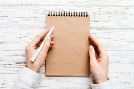 Woman hand with pencil writing on notebook. Woman working on office table. Female hand holding...