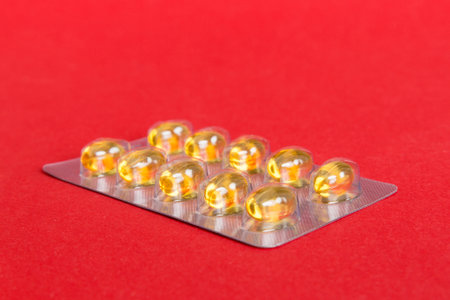 Blister package with fish oil capsules on color background. Medicine pills on a light background. Medicines and prescription pills flat lay background. Yellow medical tablets in blister.の写真素材