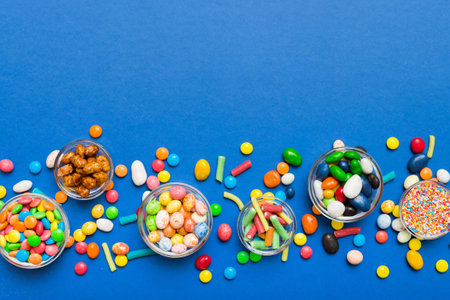different colored round candy in bowl and jars. Top view of large variety of sweets and candies with copy space.の写真素材