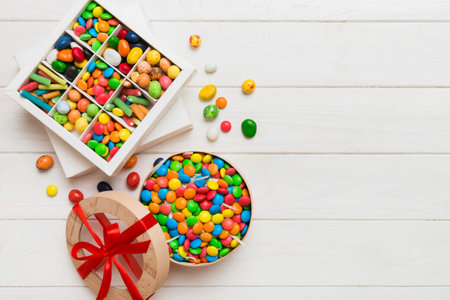 Set of different sweet candy in a paper box with a satin ribbon on a colored background. Holiday concept.の写真素材