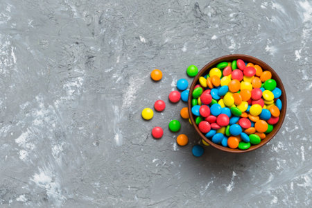 Multicolored candies in a bowl on a colored background. birthday and holiday concept. Top view with copy space.の写真素材