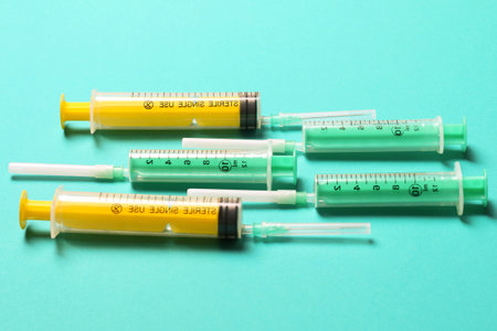 Top view of medical syringes with needles at blue background with copy space. Injection treatment...
