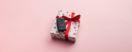 Give gift car key concept top view. Present box with red ribbon bow, heart and car key on coral colored background.の写真素材