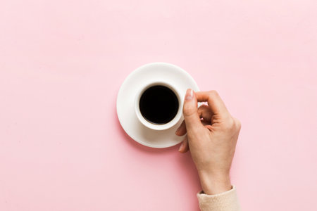 Minimalistic style woman hand holding a cup of coffee on Colored background. Flat lay, top view...