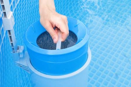 girl cleans skimmer for the frame pool. Contaminated pool cleaning concept.