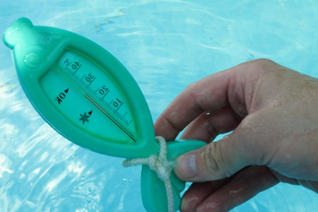 a man hand checks the temperature with a thermometer on a sunny day.