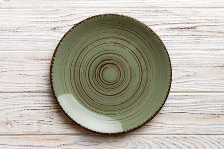 Top view of empty green plate on wooden background. Empty space for your design.