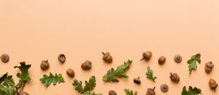 Branch with green oak tree leaves and acorns on colored background, close up top view.