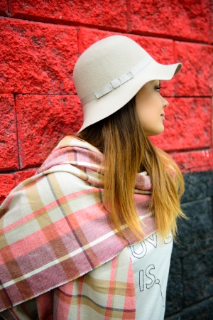 a beautiful woman is posing next to a red wall 