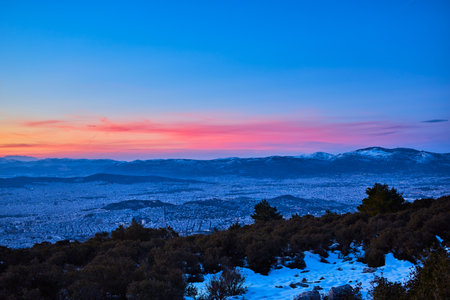 Beautiful sunset with pink orange blue sky over Athens of Greece city snow at foreground and the mountains at backgroundの写真素材