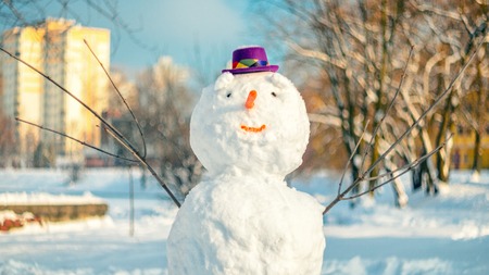 Snowman with purple hat in city parkの写真素材