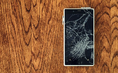 Top view of Smartphone with broken screen on wooden table.の写真素材