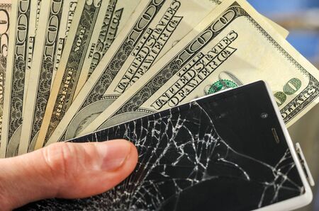 White Smartphone with broken screen in human hands on blured nature background. Need new smartphone, a waste of conceptの写真素材